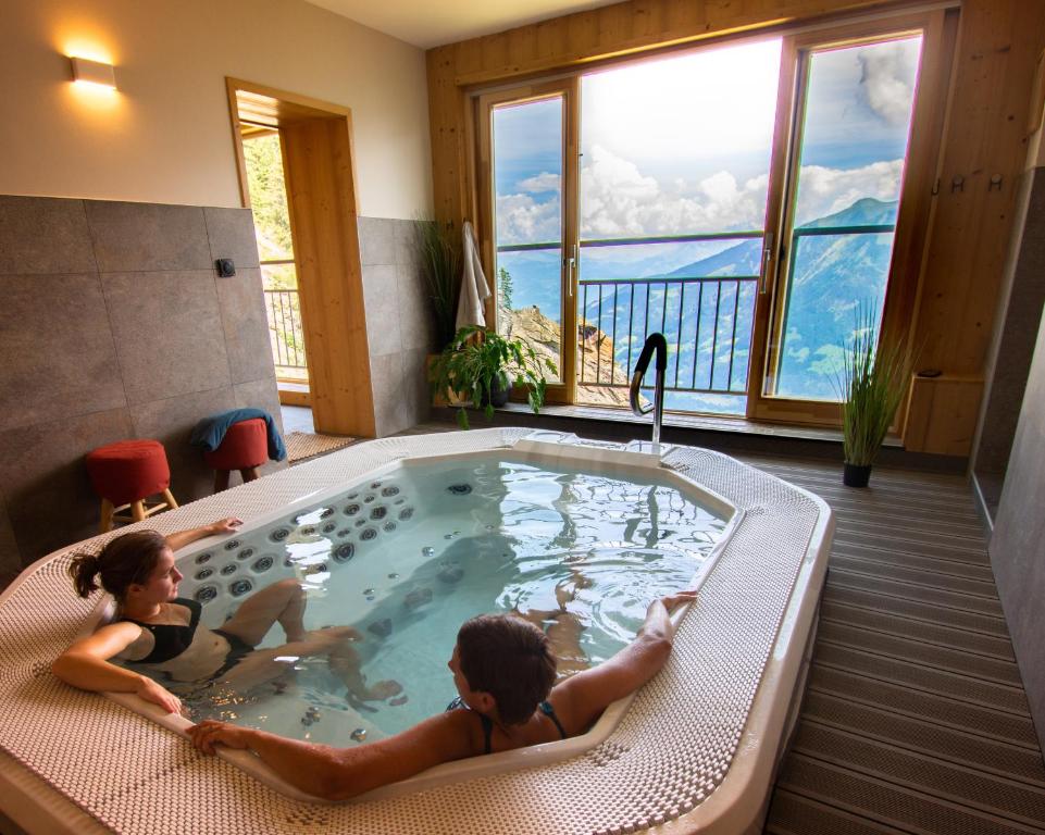 twee meisjes in een jacuzzi in een kamer bij Hôtel Plein Ciel in Champéry