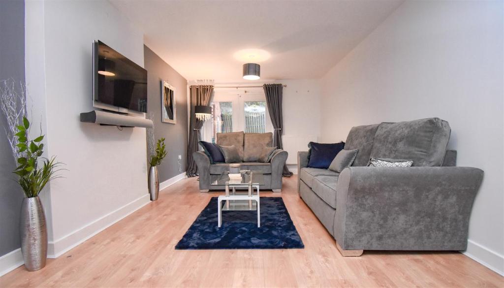uma sala de estar com dois sofás e uma televisão em Foxley Place: MK City house for large groups em Milton Keynes