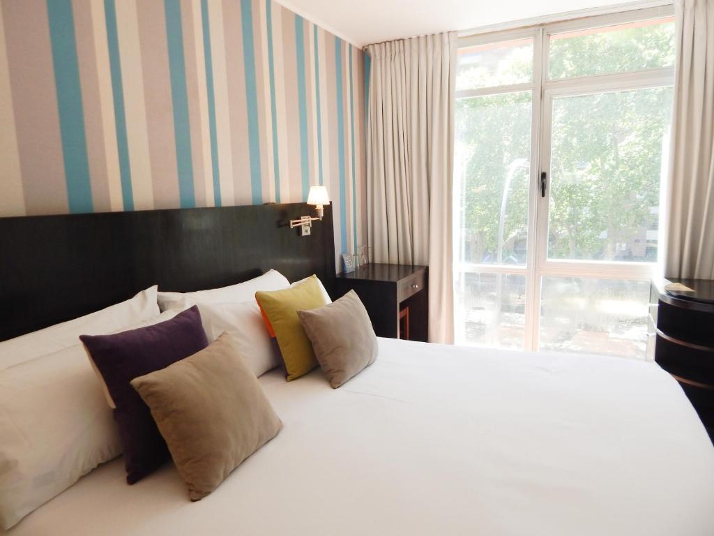 a bedroom with a white bed with pillows and a window at Ribera Sur Hotel in Buenos Aires