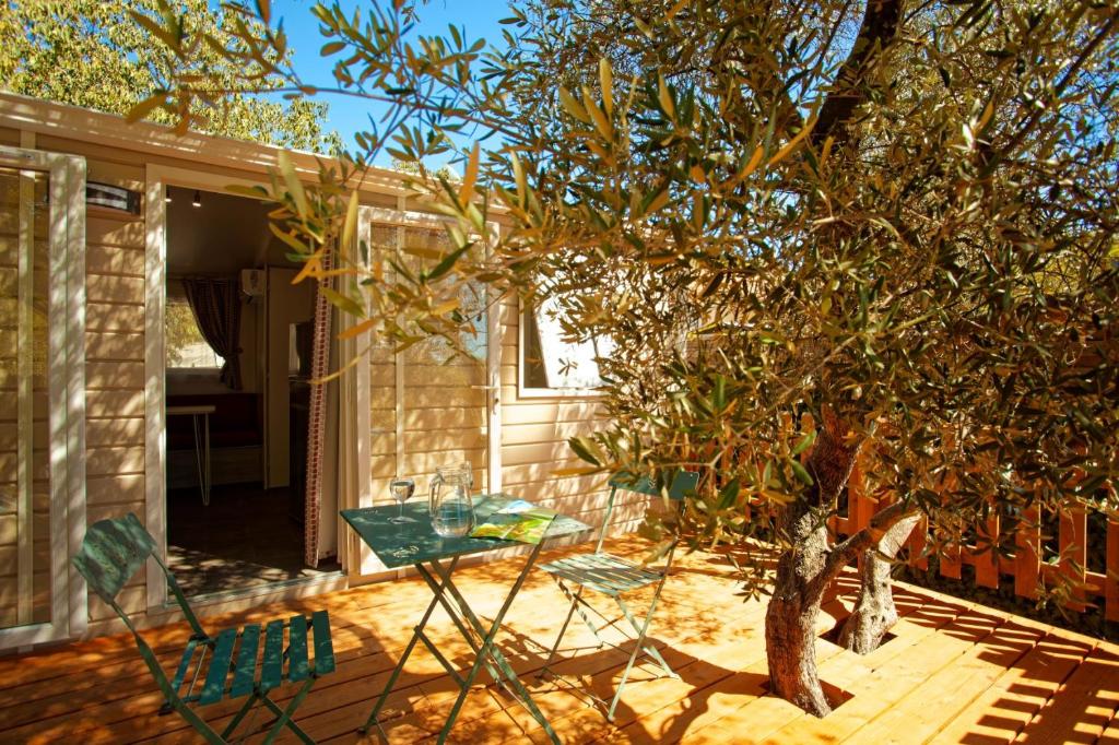 une terrasse avec une table et des chaises à côté d'un arbre dans l'établissement Camping l'Olivier Junas, à Junas