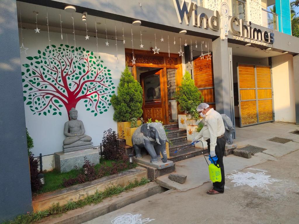 a man standing in front of a building with a tree mural at Wind chimes in Auroville