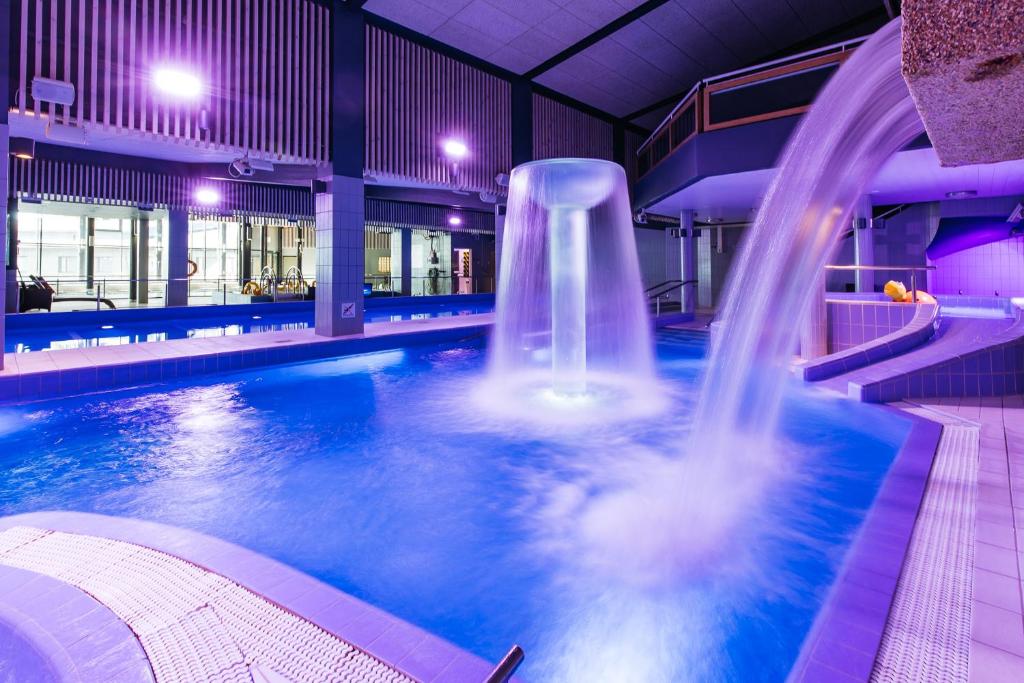 a swimming pool with a waterfall in a building at Spa Hotel Härmä - Härmän Kylpylä in Ylihärmä