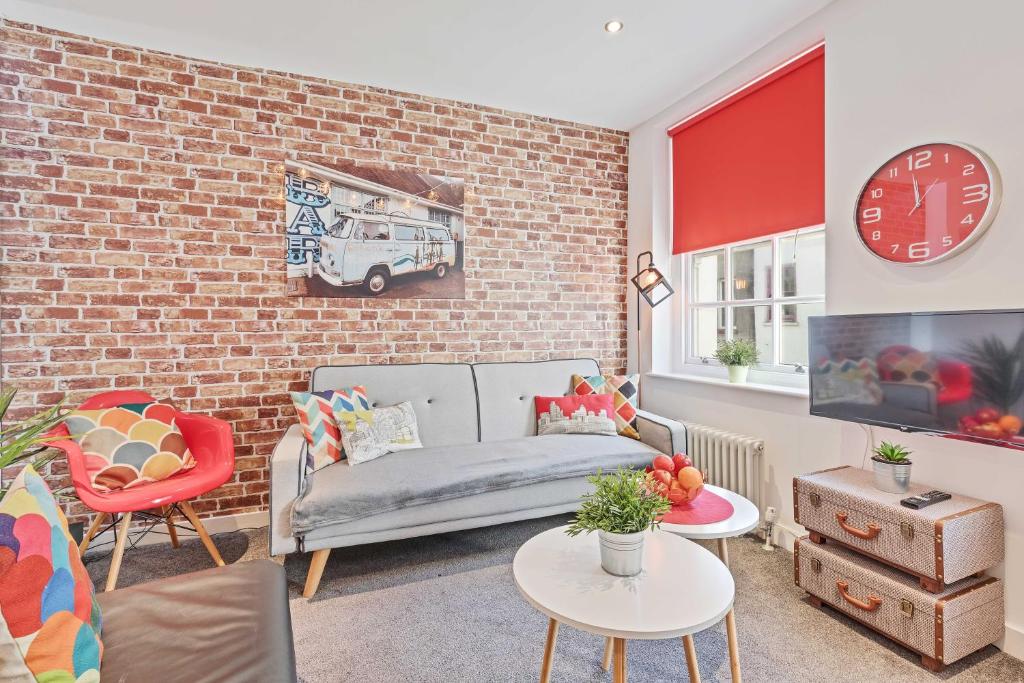 a living room with a couch and a brick wall at Majestic Mews Apartment with Free Parking - By My Getaways in Brighton & Hove