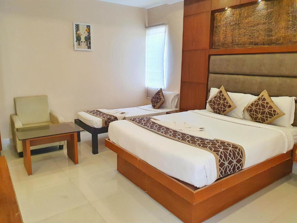 a hotel room with two beds and a chair at The Hydel Park - Business Class Hotel - Near Central Railway Station in Chennai