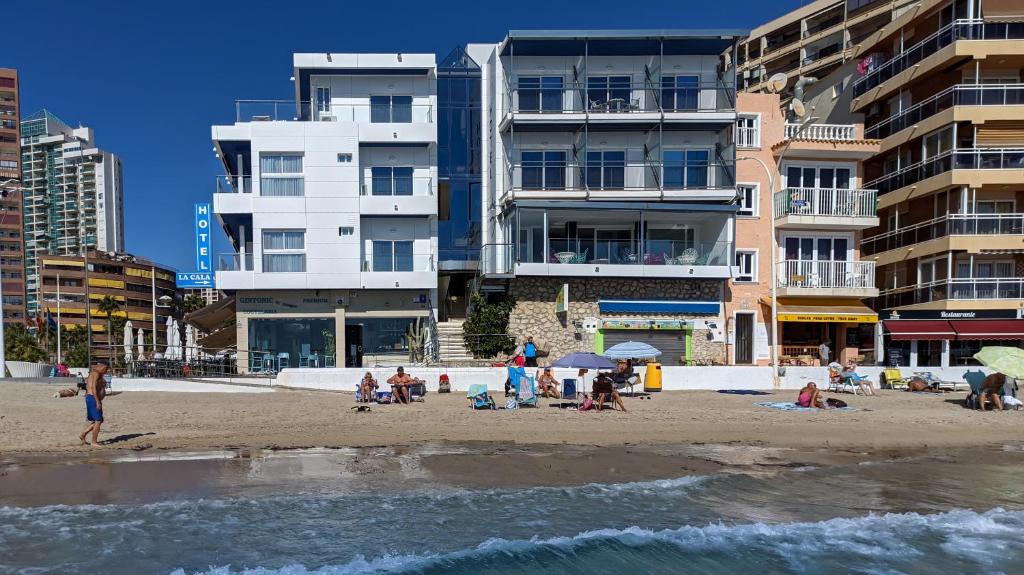 um grupo de pessoas numa praia com edifícios em Hotel La Cala Finestrat em Cala de Finestrat