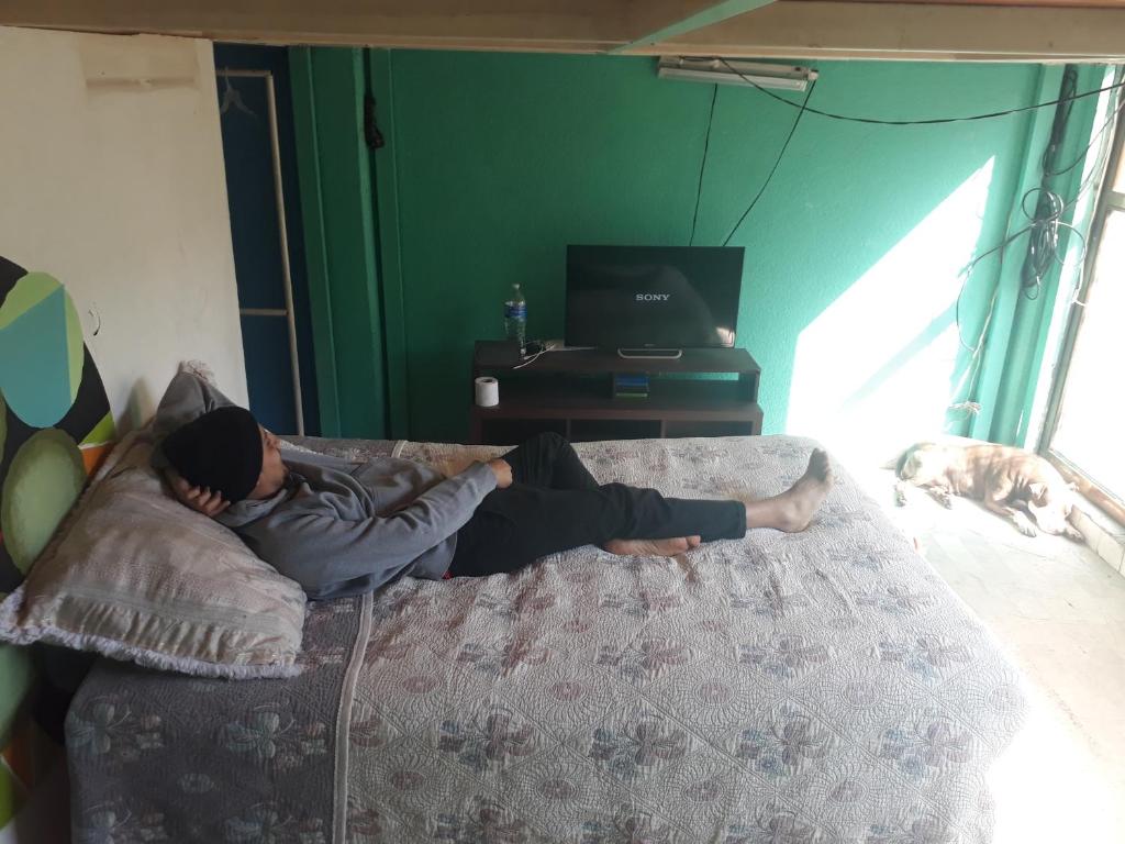 a man laying on a bed in a bedroom with a dog at Suit compartida con amenidades in Mexico City