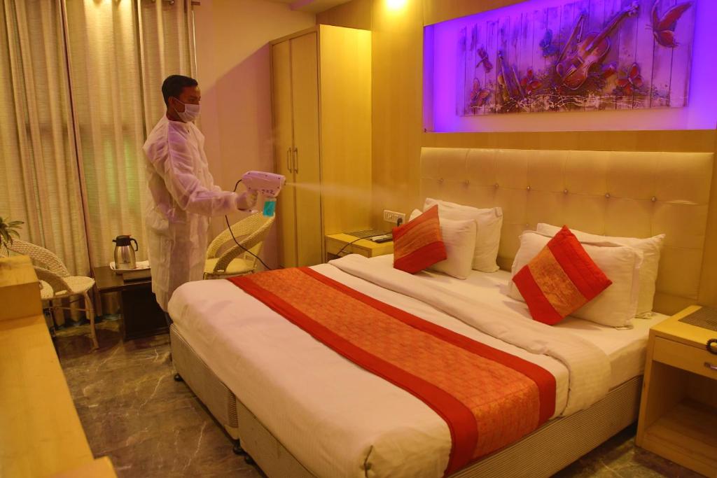 a man standing next to a bed in a room at Hotel Shelton in New Delhi