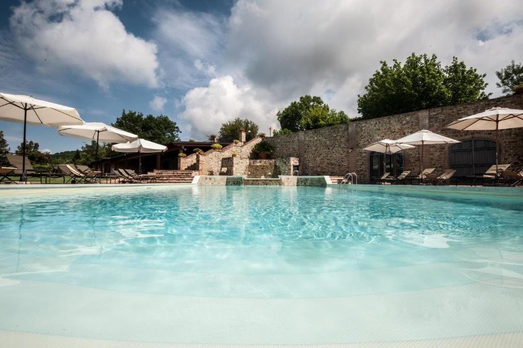 una gran piscina con agua azul y sombrillas en La Fonte Di Montebuono, en Magione