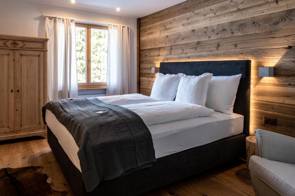 a bedroom with a large bed with a wooden wall at Typically Swiss Hotel Ermitage in Kandersteg