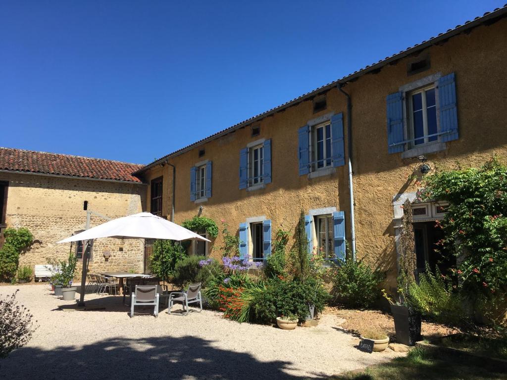 a patio with a table and an umbrella in front of a building at Le Clos Galan in Galan