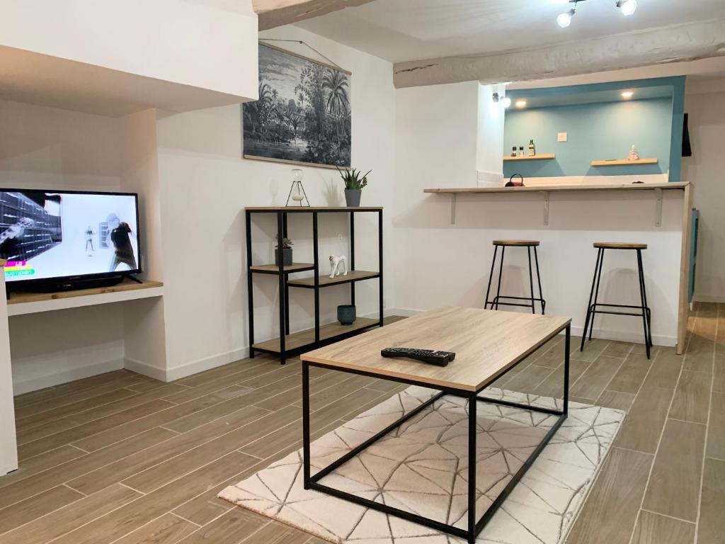 uma sala de estar com uma mesa e uma televisão em Chez Tom - au pied des musées em Grasse