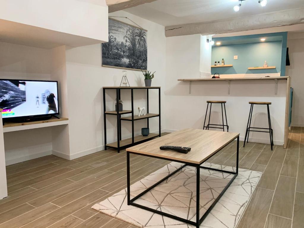 a living room with a table and a tv at Chez Tom - au pied des musées in Grasse
