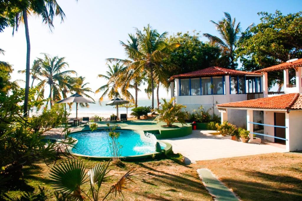 a villa with a swimming pool in front of the beach at Pousada Les Alizes in Icaraí