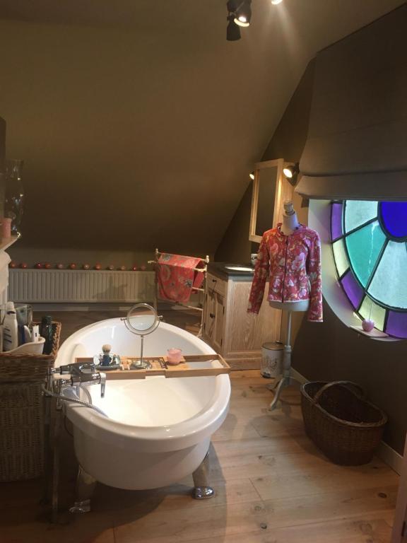 a bathroom with a bath tub and a stained glass window at Guesthouse &#39;t Goed Leven in Stokrooie