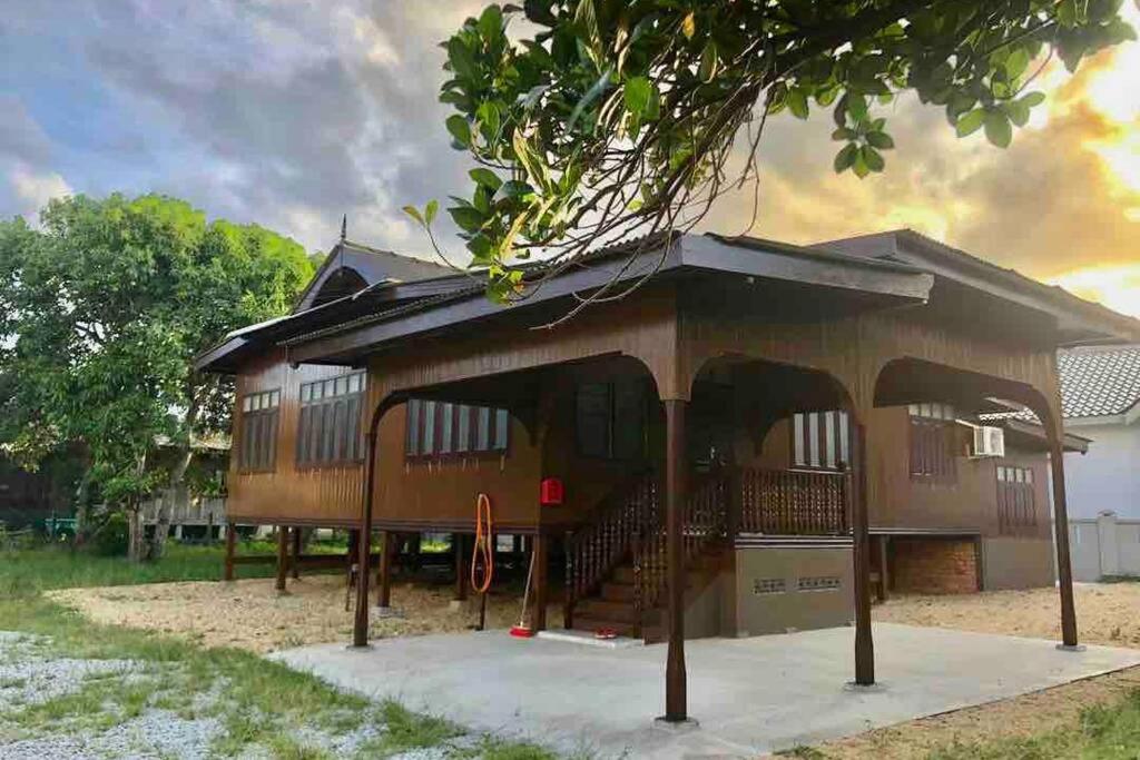 ein Gebäude mit einer Veranda und einem Baum in der Unterkunft De RhuMaa Homestay in Kuala Terengganu