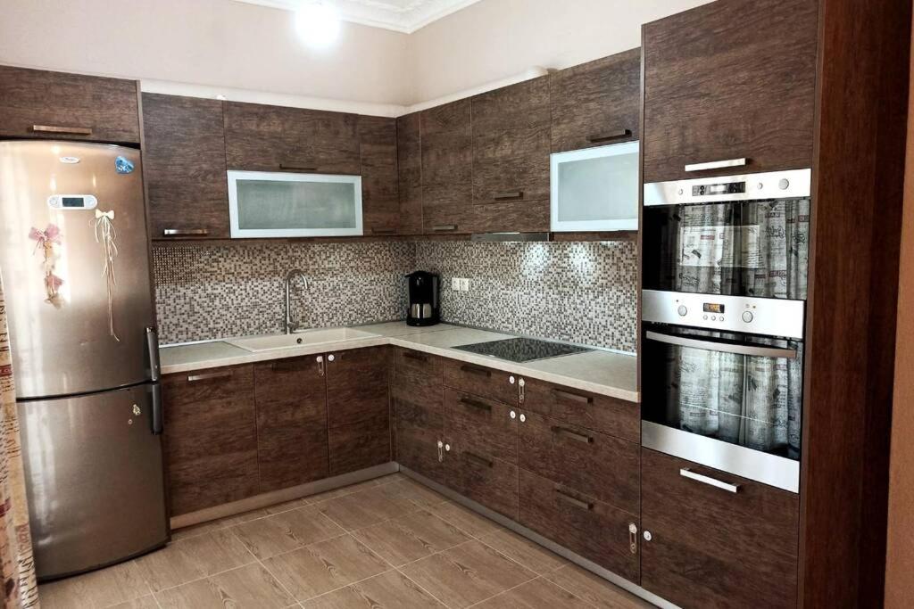 a kitchen with wooden cabinets and a stainless steel refrigerator at Myrto Guesthouse in Kavos