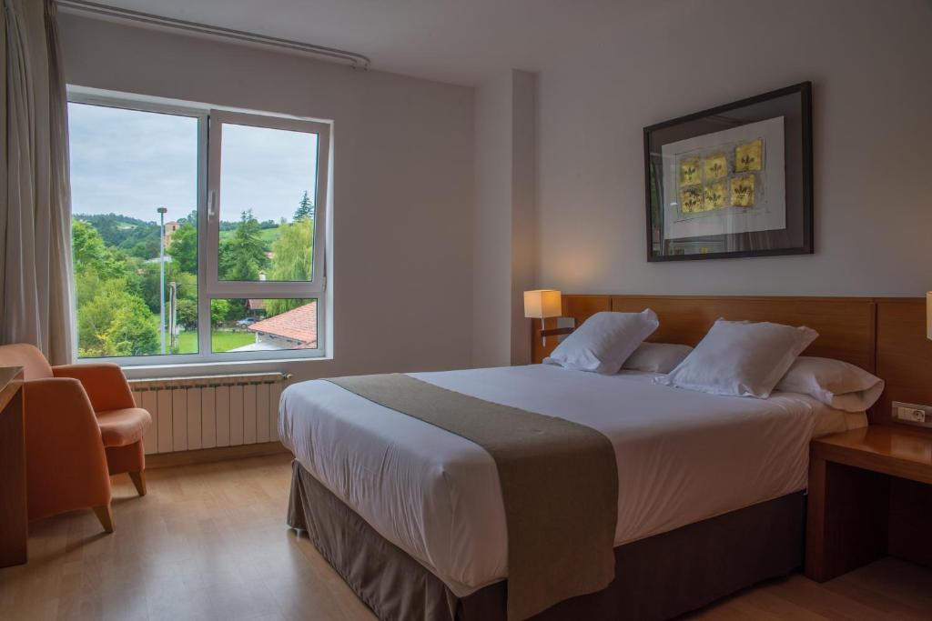 a bedroom with a large bed and a large window at Hotel Miera in Liérganes