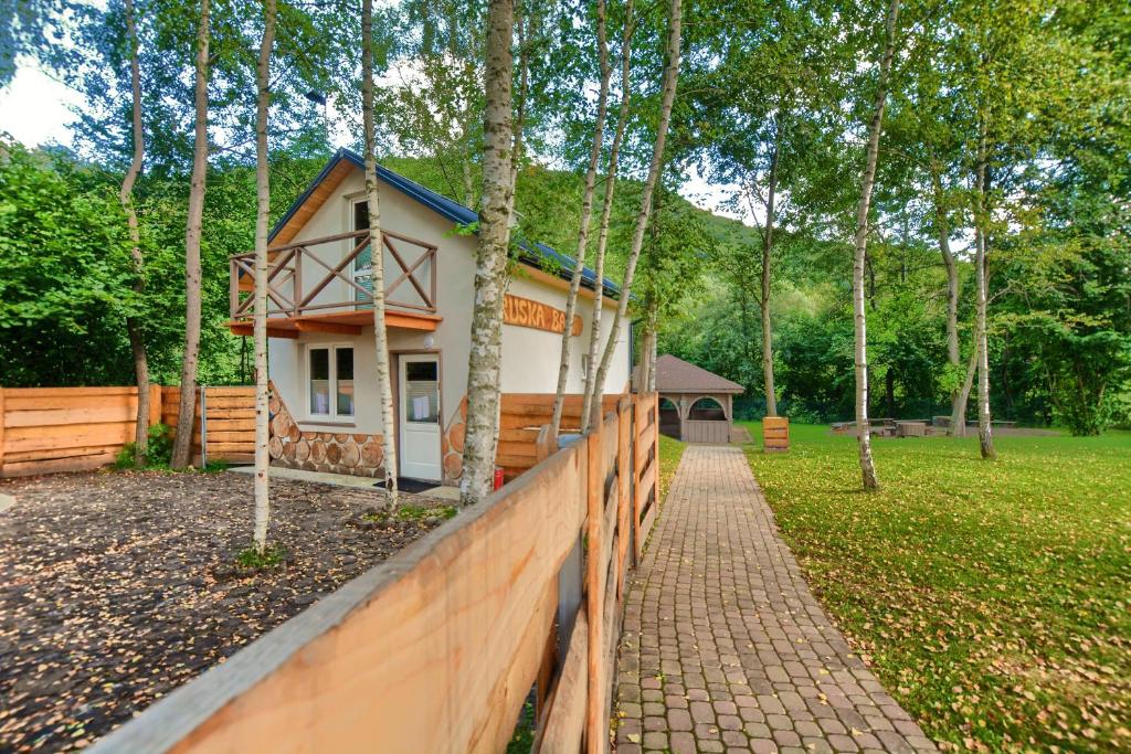 una pequeña casa con una valla al lado de un campo en RUSKA BANIA, en Polańczyk