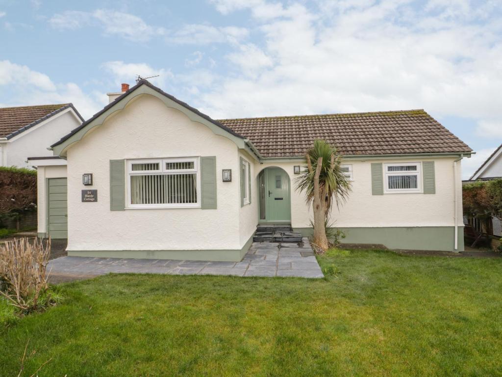 a white house with a palm tree in the yard at Hardy Cottage in Benllech