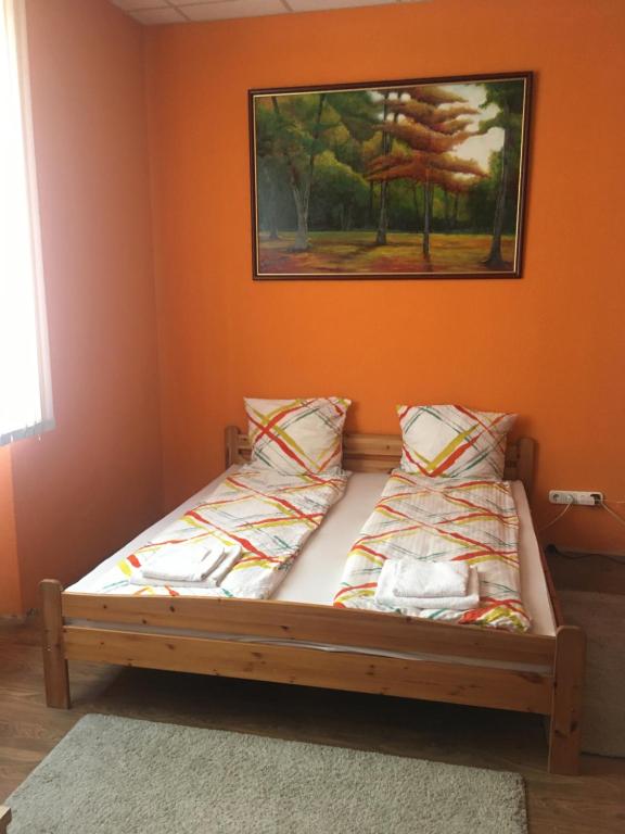 uma cama num quarto com uma parede laranja em Andrea Vendégház Székesfehérvár em Székesfehérvár