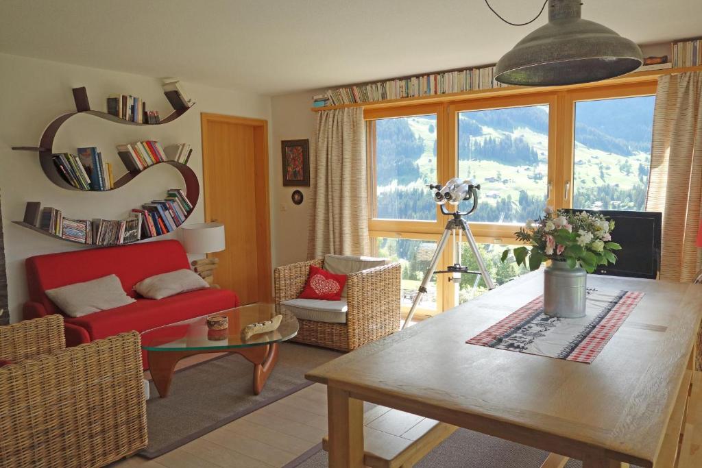 a living room with a table and a red chair at Ferienwohnung Gartenweg in Adelboden