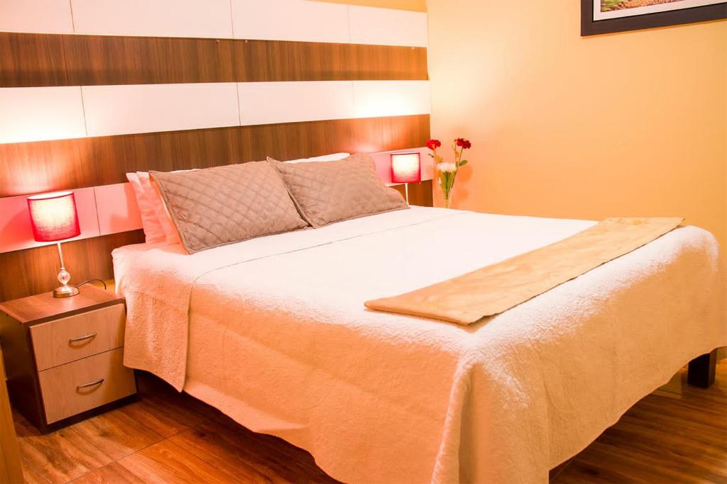 1 dormitorio con 1 cama blanca grande y 2 lámparas en Serk'ana Suite Hostal, en Arequipa