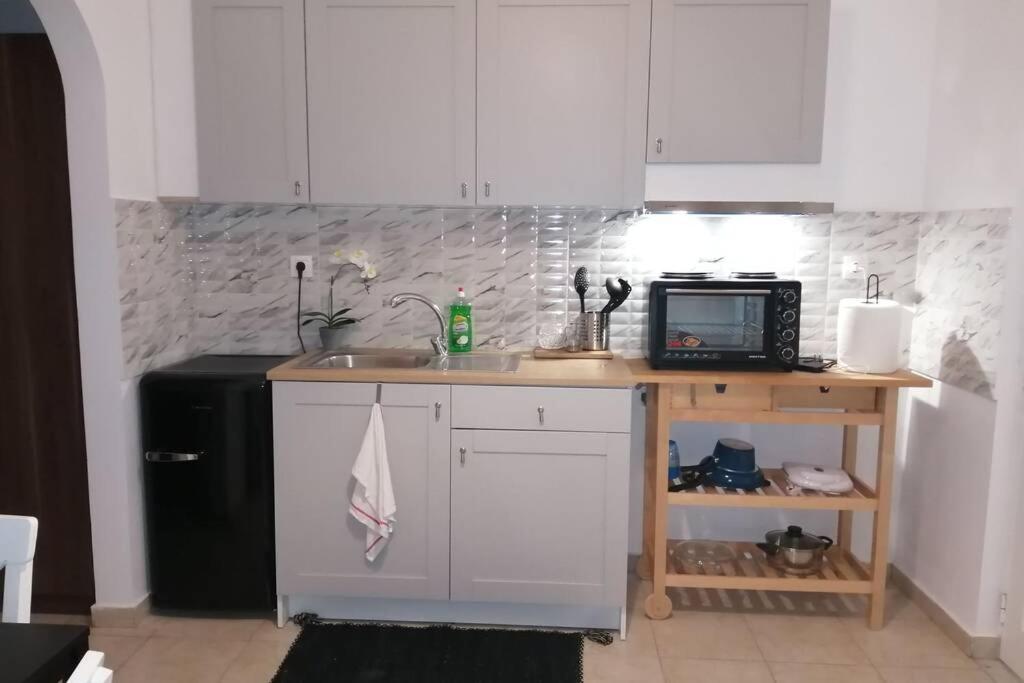 uma cozinha com armários brancos, um lavatório e um frigorífico em Cozy apartment em Triánta