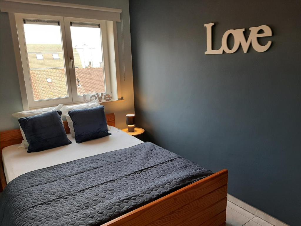 a bedroom with a bed and a sign that says love at Residentie Da Vinci Middelkerke in Middelkerke
