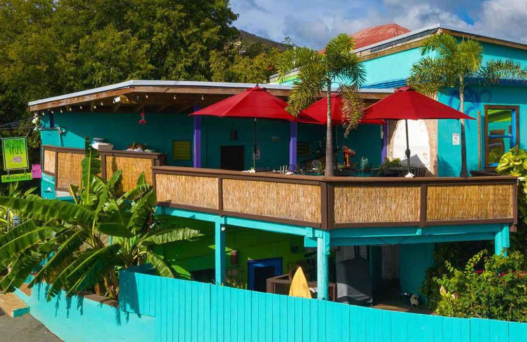 a blue house with red umbrellas on a deck at St John Inn in Contant