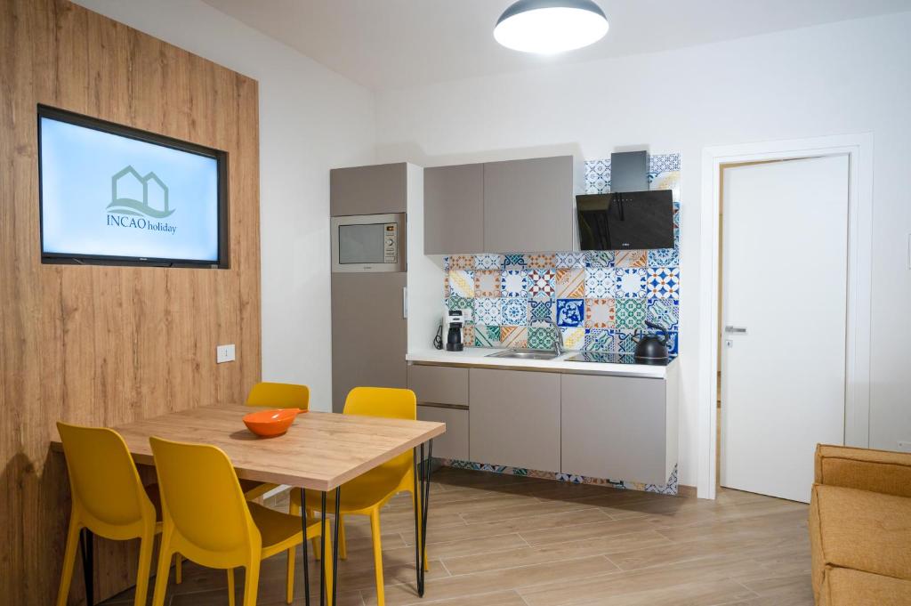 a kitchen and dining room with a table and yellow chairs at Incao Holiday Candeloro House in Cefalù