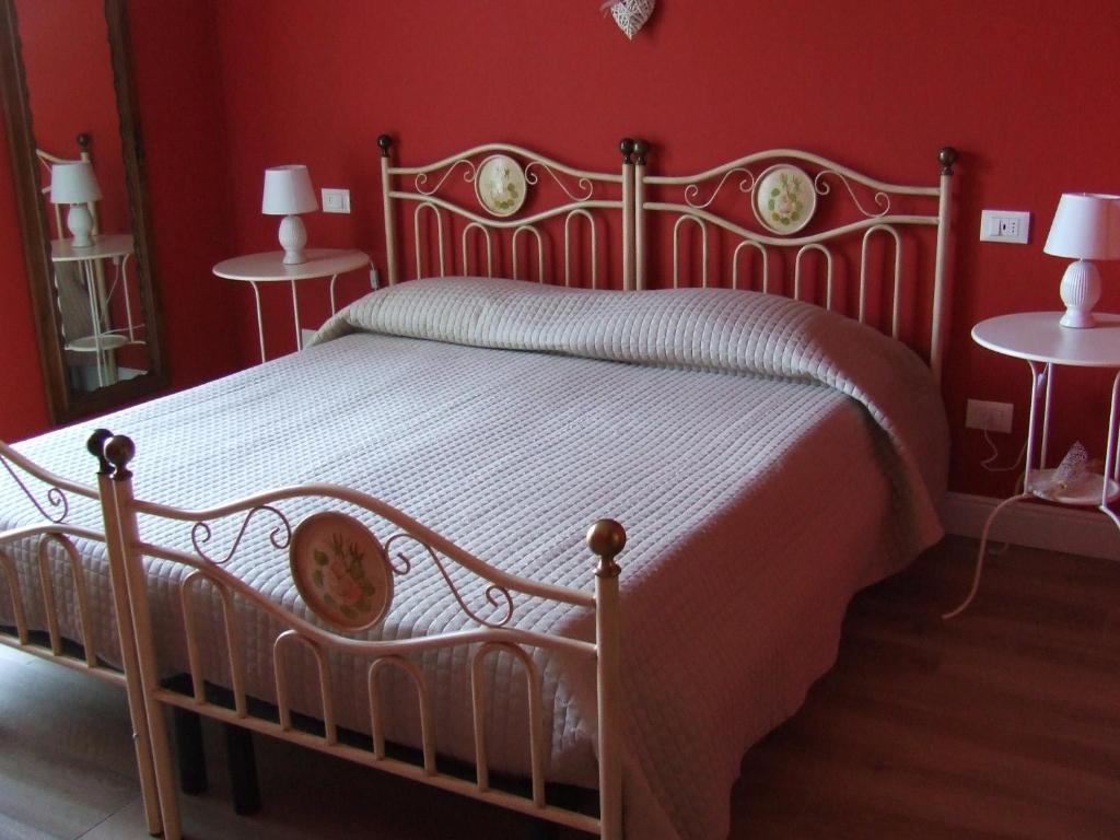 een bed in een rode slaapkamer met 2 tafels bij B&B Solstizio d'estate in San Felice del Benaco