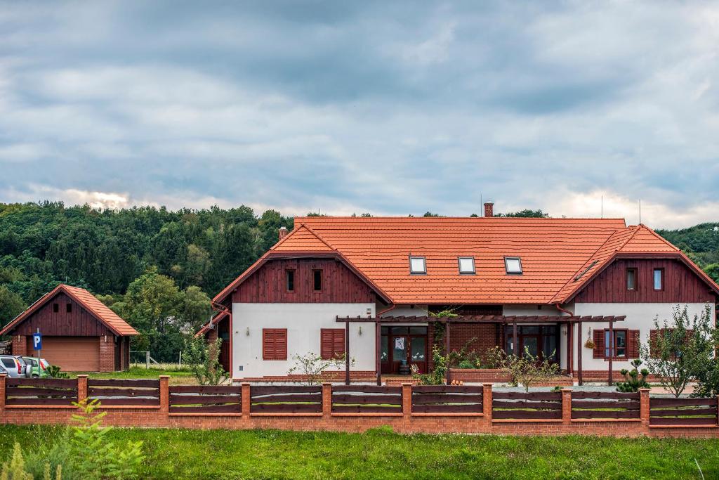 ein Haus mit einem orangenen Dach und einem Zaun in der Unterkunft Naturpark Vendégház in Alsószölnök