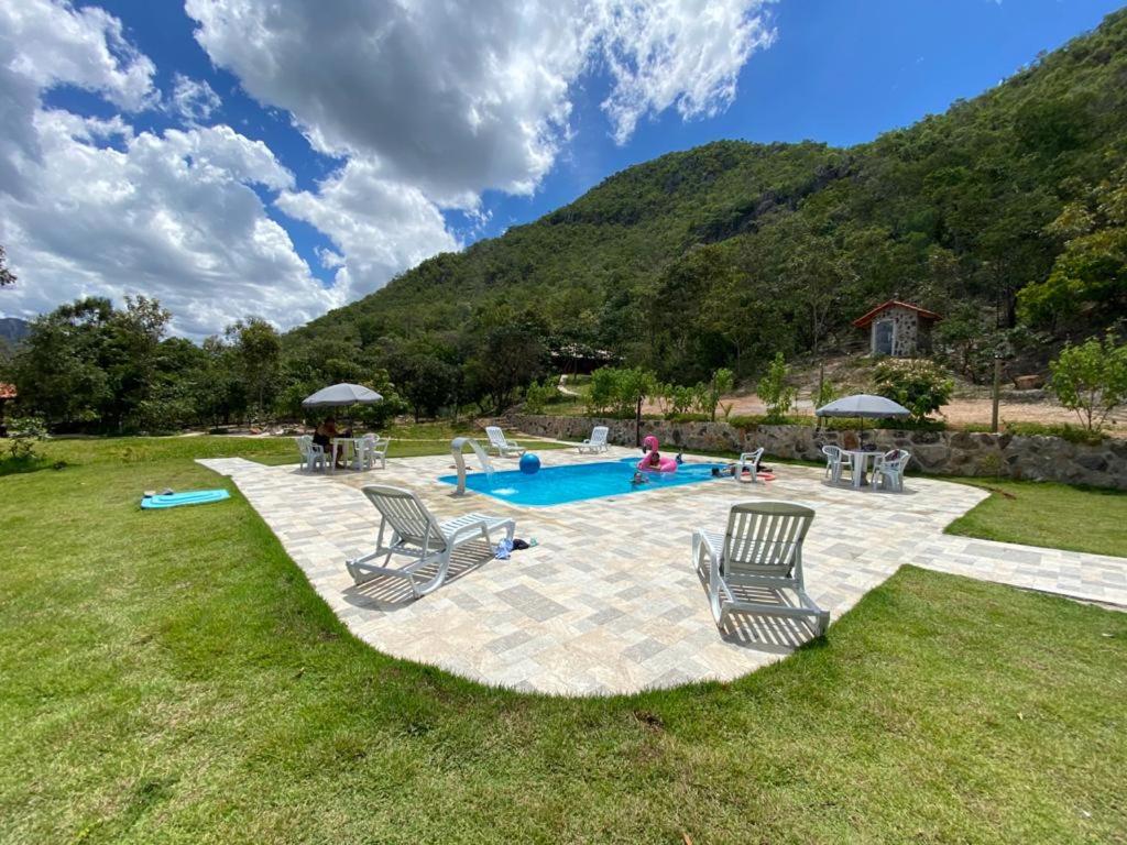 a patio with chairs and a swimming pool in a yard at Chácara Recanto da Paz in Cavalcante