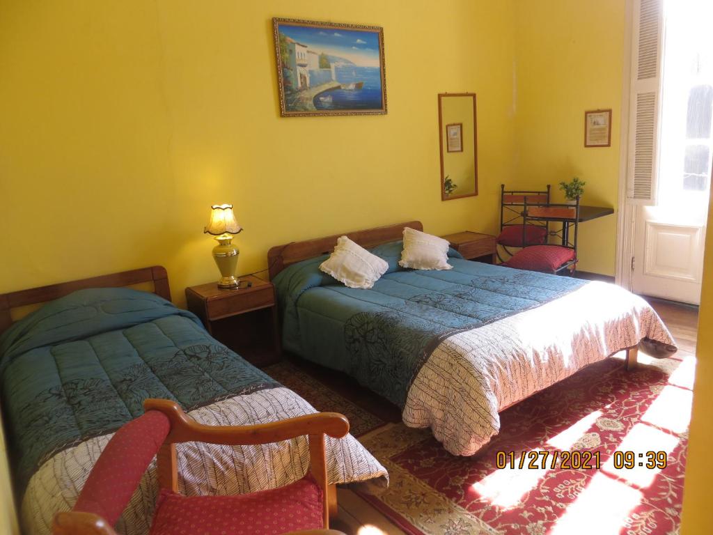 Un dormitorio con 2 camas y una silla. en Hostal El Rincon Marino, en Valparaíso