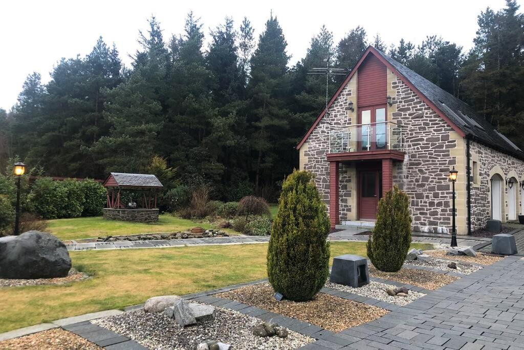 een stenen huis met een tuin en een prieel bij Struan Coach house in gated residence in Stirling