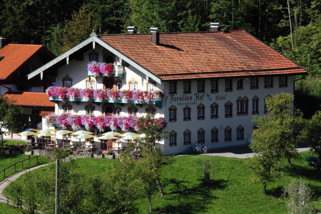 - un grand bâtiment blanc avec des fleurs dans l'établissement Forellenhof, à Siegsdorf