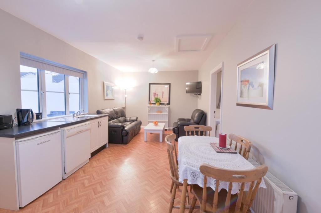 a kitchen and a living room with a table and chairs at Ocean Breeze Apartment in Lahinch