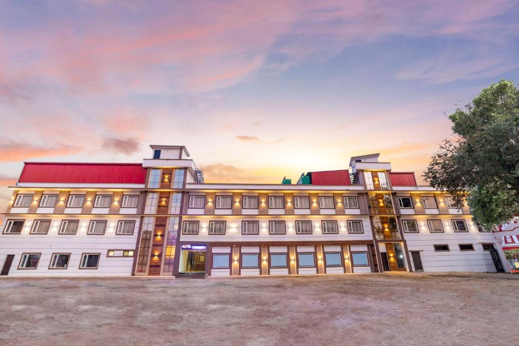 a large white building with a red roof at Hotel Trimurti in Haridwār