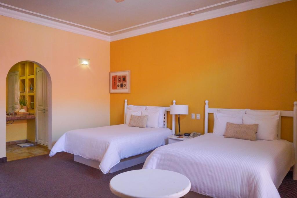 two beds in a room with yellow walls at Gran Hotel de Querétaro in Querétaro