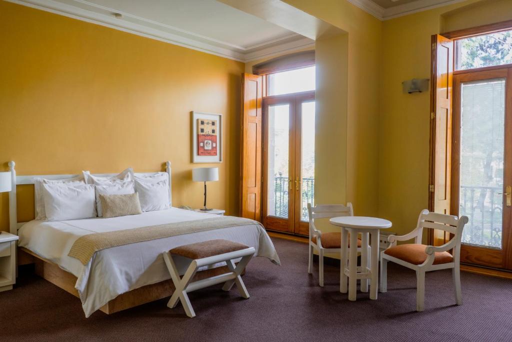 a bedroom with a bed and a table and chairs at Gran Hotel de Querétaro in Querétaro