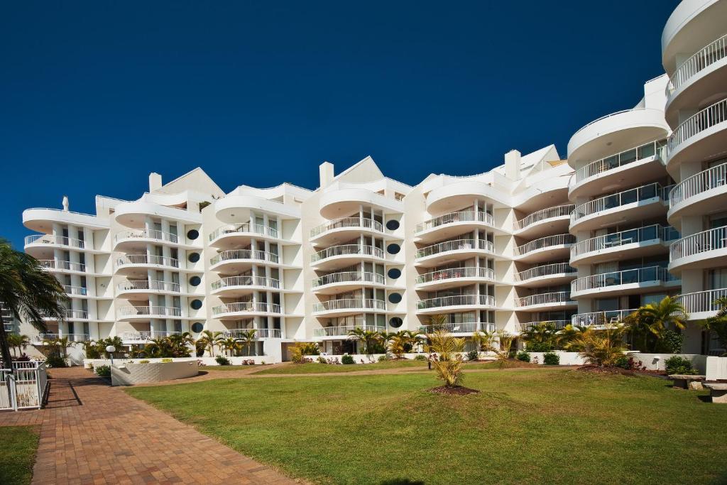 a large white building with a palm tree in front of it at Osprey Apartments in Mooloolaba