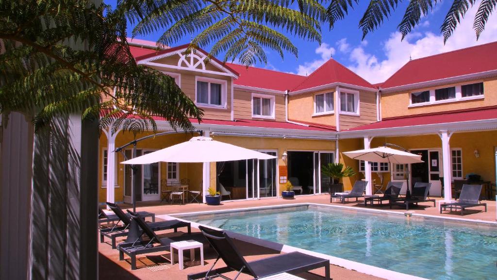 - une piscine avec des chaises et des parasols à côté d'une maison dans l'établissement Hotel Le Cilaos, à Cilaos