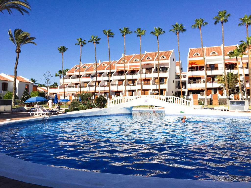 una piscina di fronte a un hotel con palme di LUX&2Jacuzzi. NEW! Golden Mile Las Americas, Parque Santiago 2. Pool heated Sea water 2 BDR a Playa de las Americas