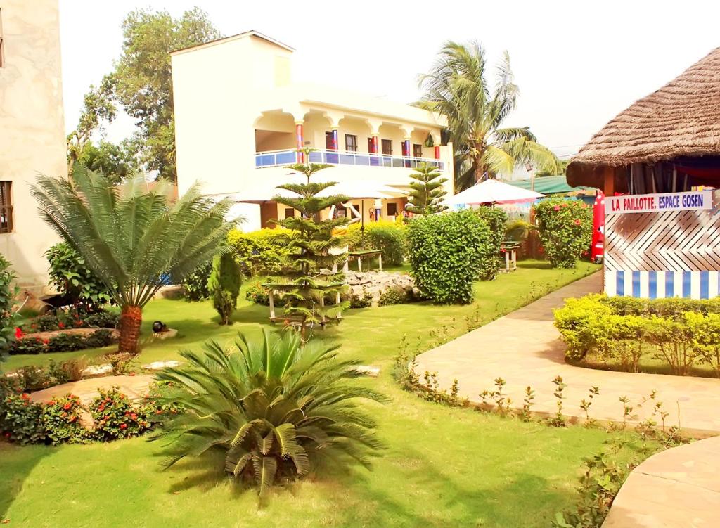 ein Resort mit einem Garten mit Palmen und einem Gebäude in der Unterkunft Hotel Ganiela in Palimé