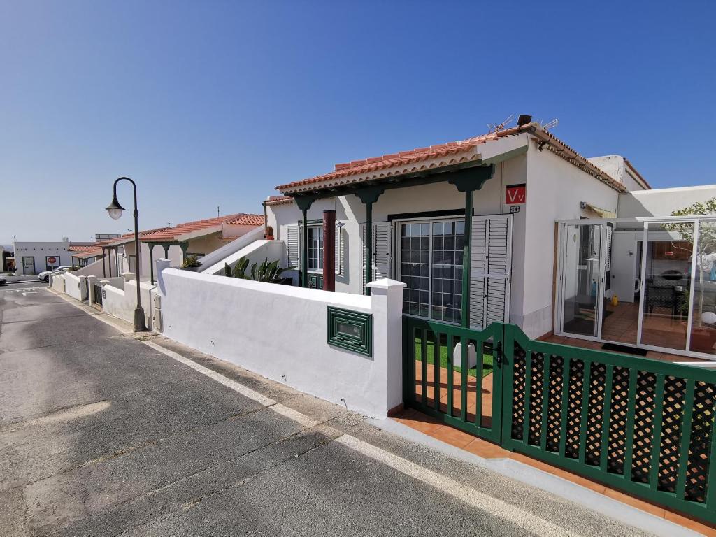 a house with a green fence next to a street at La Casa del Sol, Abades in Abades