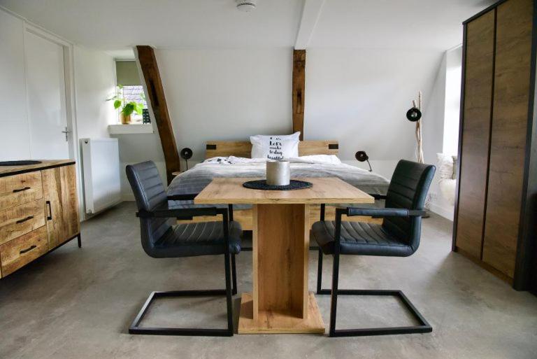 een tafel en stoelen in een kamer met een bed bij De Slaapmuts in Winsum