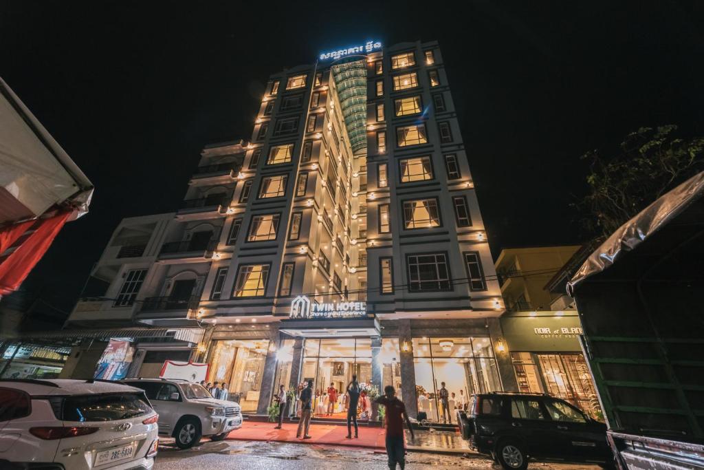 a tall building with people standing in front of it at Twin Hotel in Kampot
