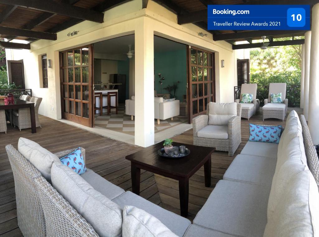 een patio met witte banken en een tafel bij Blue Bay BEACH Villa 25 3-min beach-pool-golf in Blauw Baai