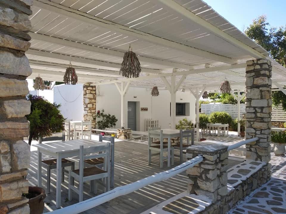a patio with tables and chairs under a pergola at Surfing Beach Village Paros in Santa Maria