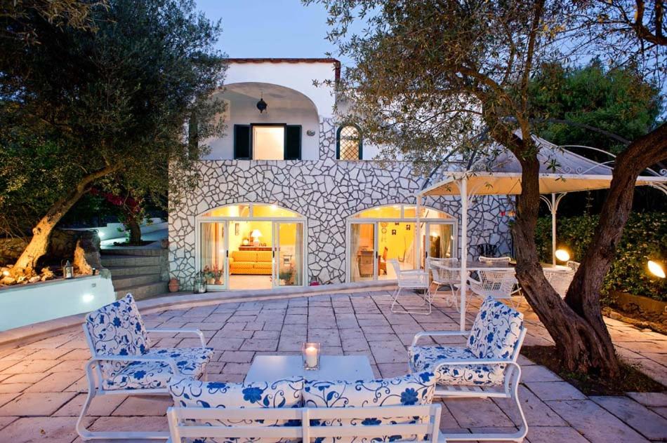 un patio avec des chaises et des tables en face d'un bâtiment dans l'établissement La Draghina B&B Capri, à Anacapri